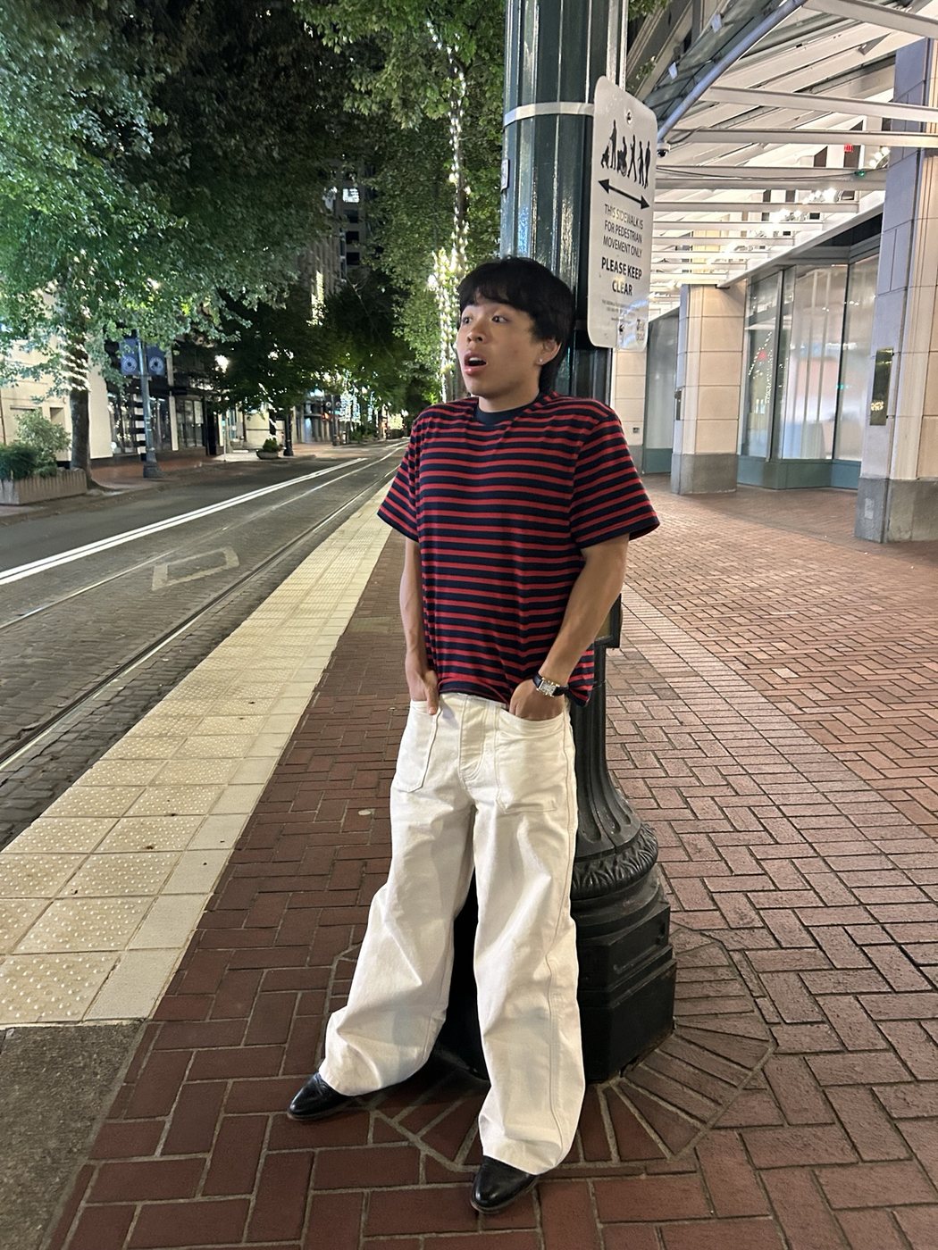 Huy leaning on a lamppost on a city street at night